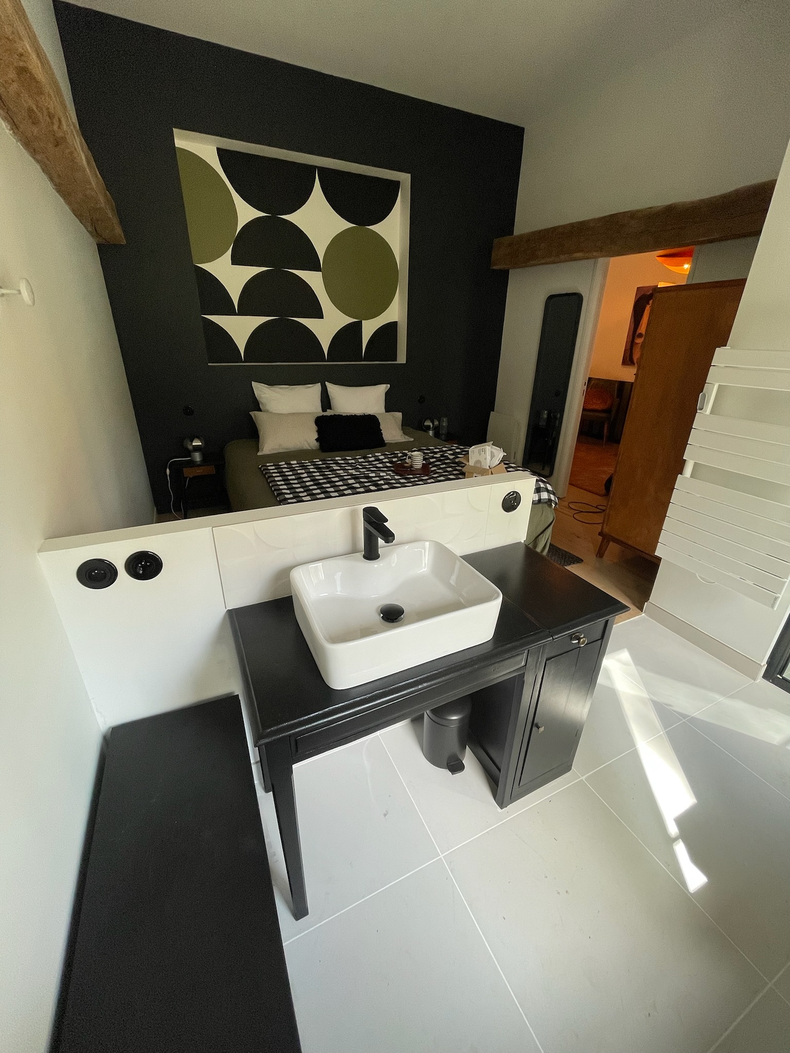 Salle de bain moderne avec mur noir, vasque blanche et interrupteurs rétro laiton