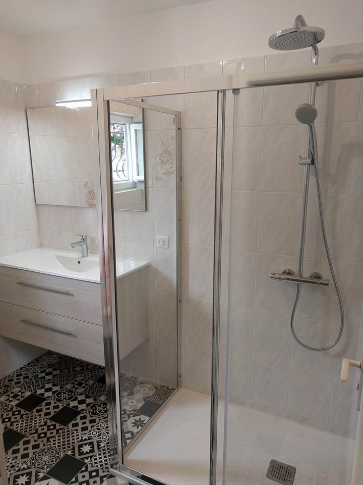 Salle de bain rénovée avec douche italienne moderne et sol en carreaux de ciment noir et blanc